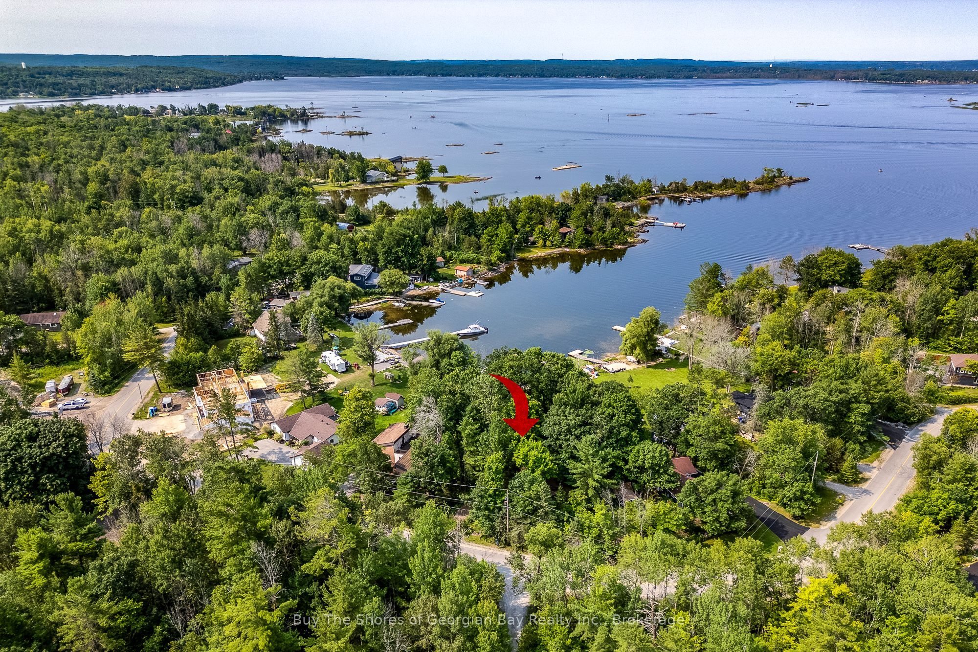 Aerial view of Forest Harbour with a red arrow marking the house among the trees and Georgian Bay beyond