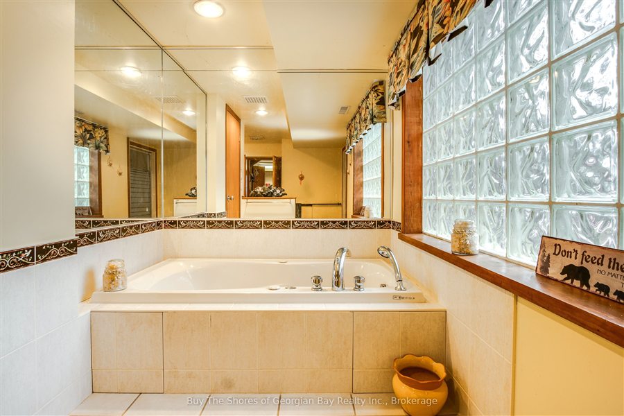 Basement bathroom with a jacuzzi tub under a glass block window and a mirrored wall
