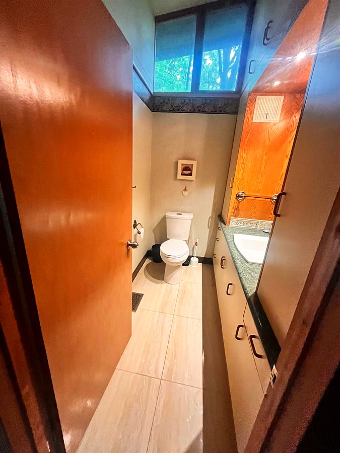 Second bathroom with warm wood walls and a window