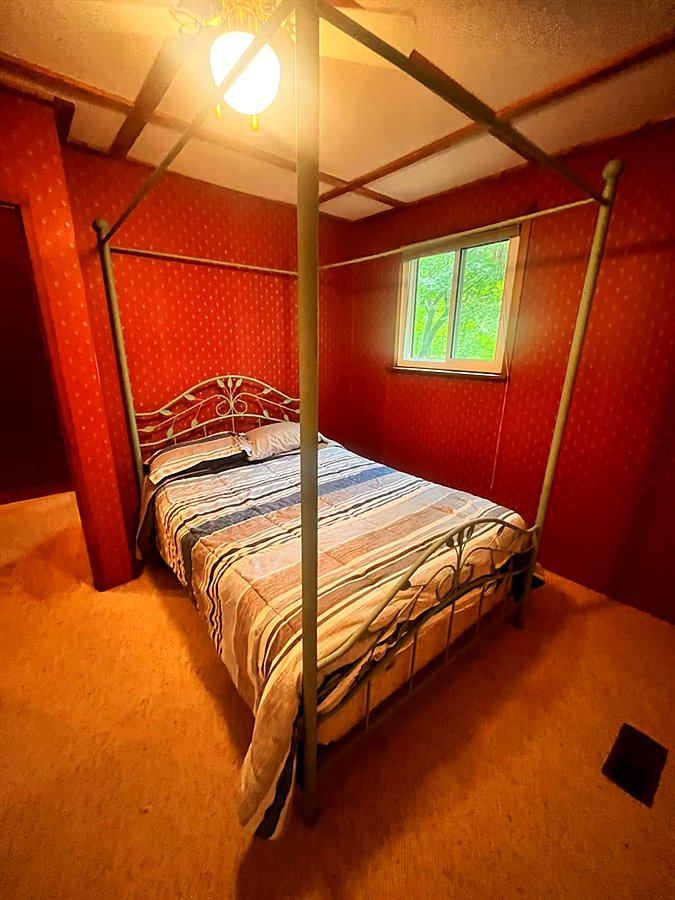 The red bedroom with a queen bed in a black iron canopy frame