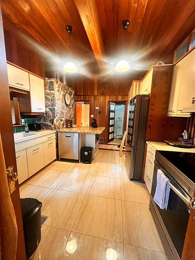 Kitchen with a beamed cedar ceiling, wood cabinets and stainless steel appliances
