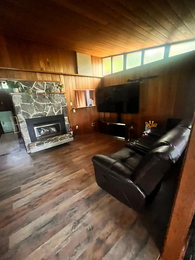 Living room with a floor-to-ceiling stone fireplace, reclining leather couches and a 75-inch smart TV